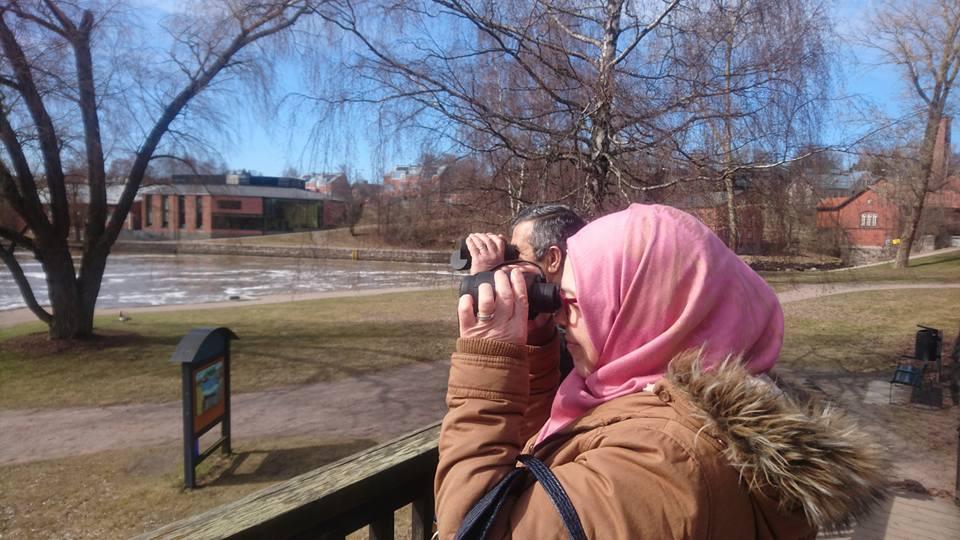 Mies sekä nainen, jolla on päässään vaaleanpunainen huivi, katselevat kiikareiden läpi.