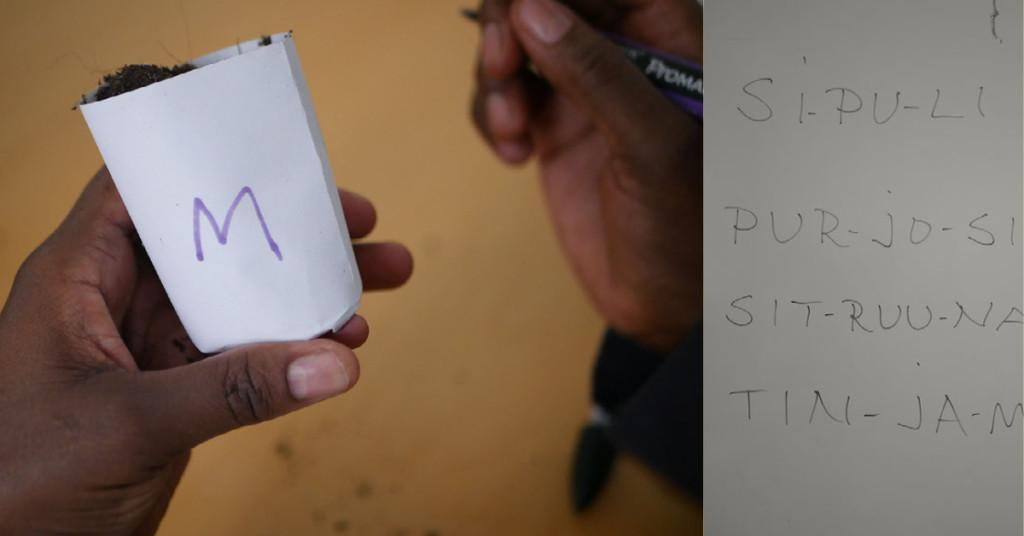 A person of colour writing to a pot and Finnish words written to the white board wall. 